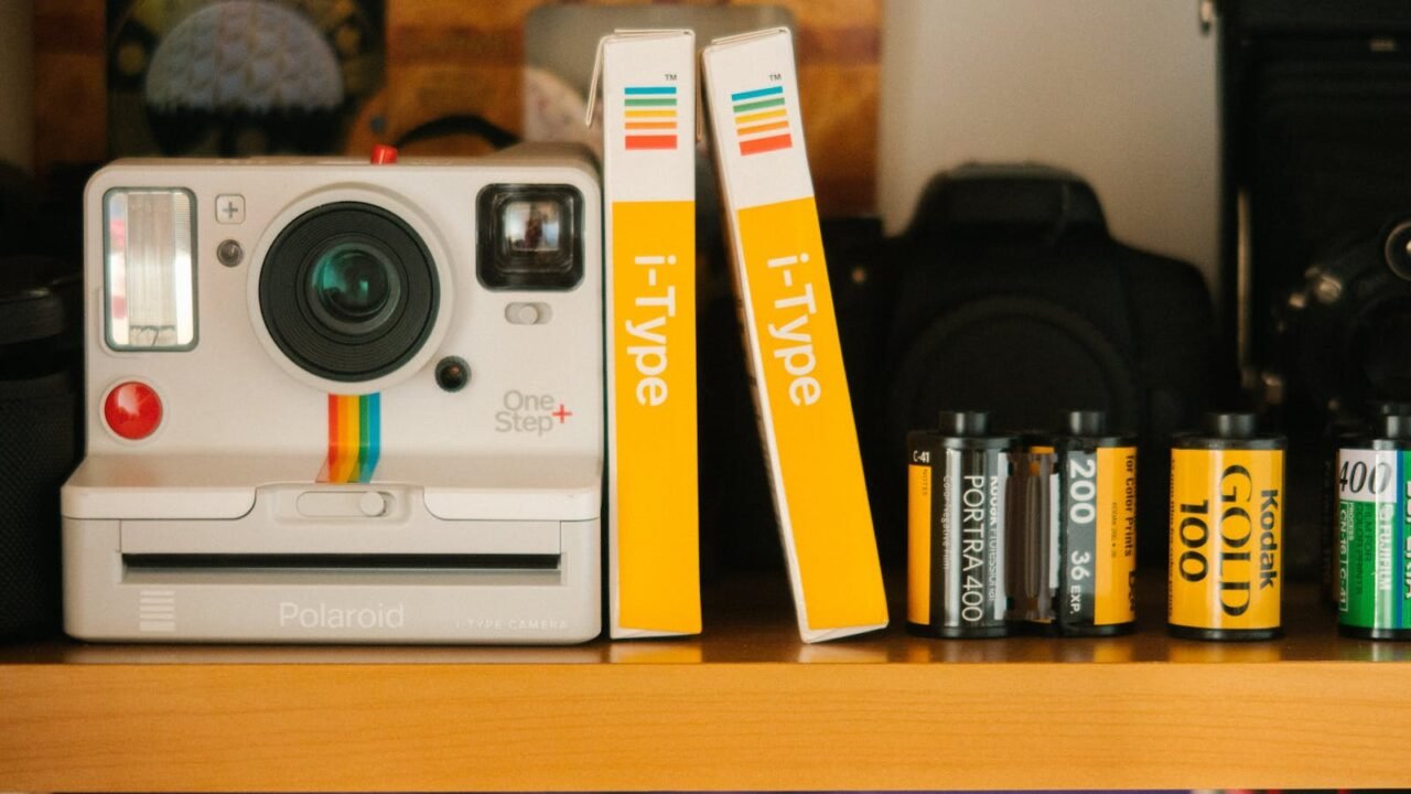 reinventarse para sobrevivir, A classic Polaroid OneStep Plus camera with film rolls on a wooden shelf, showcasing retro photography equipment.