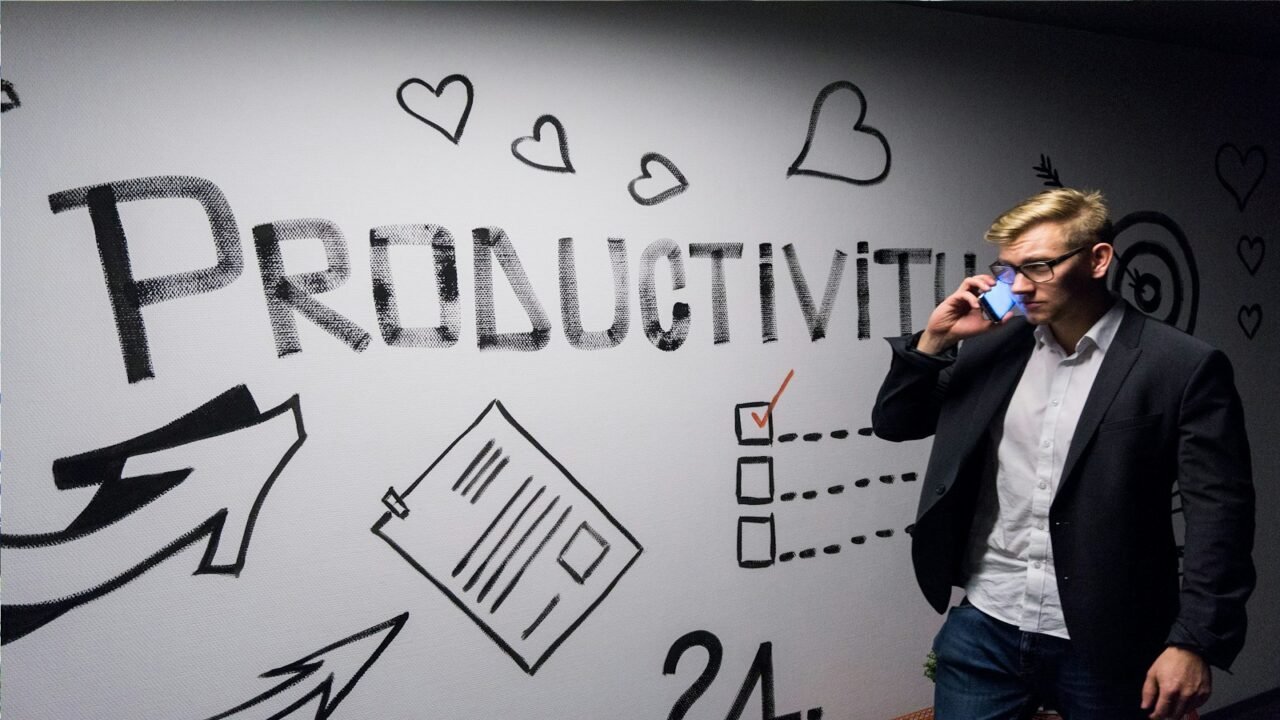 PNL y productividad, man holding smartphone looking at productivity wall decor