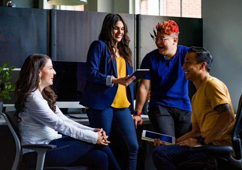 PNL para mejorar la comunicación interna, A diverse group of coworkers engaging in a lively discussion in a stylish office environment.
