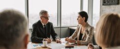 conseguir reuniones comerciales, Business professionals engaged in a strategic meeting in a modern office setting with natural light.