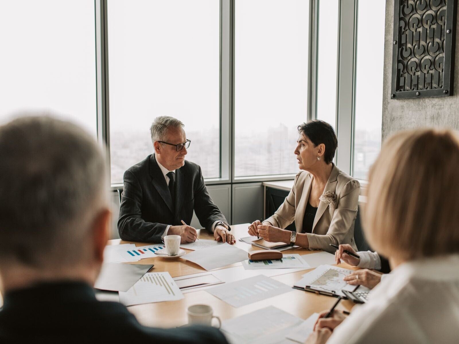 conseguir reuniones comerciales, Business professionals engaged in a strategic meeting in a modern office setting with natural light.