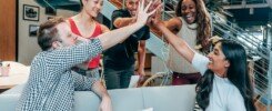 Team Building empresarial, A multicultural office team high-fiving and celebrating a successful collaboration.