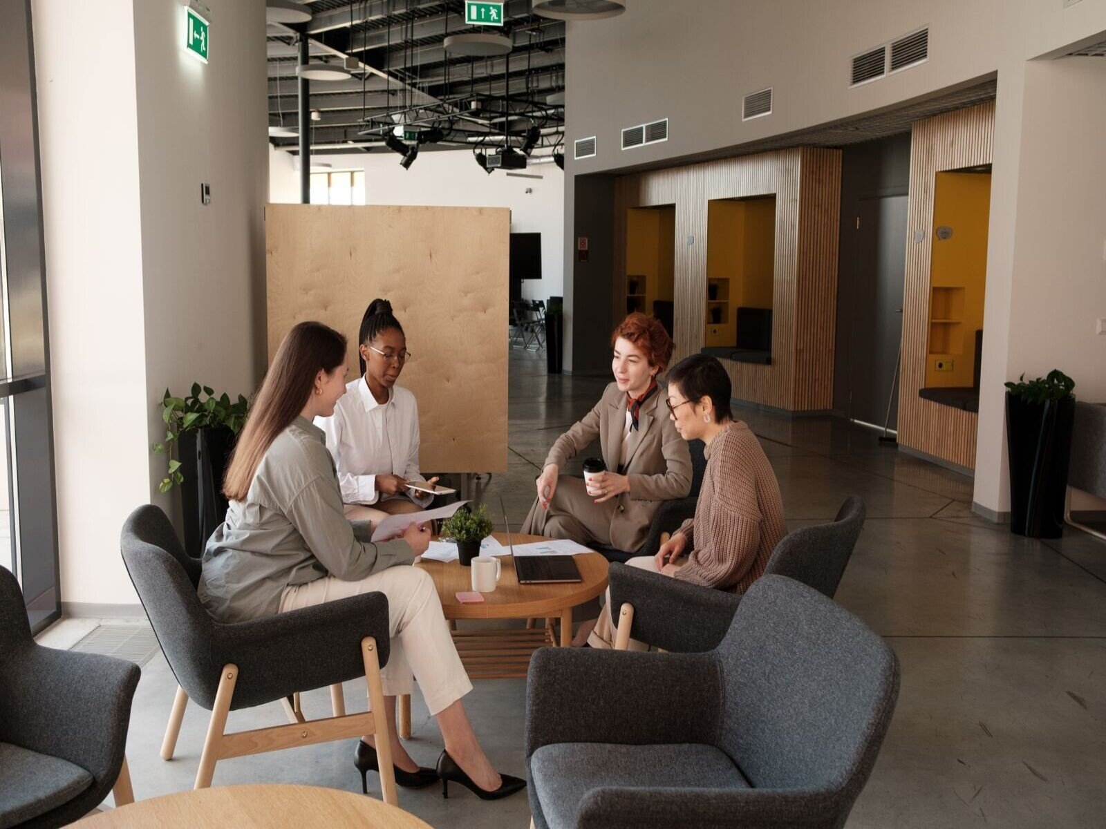 Programación Neurolingüística en las empresas, Group of professionals collaborating in a modern office lounge area, engaging in team discussions.