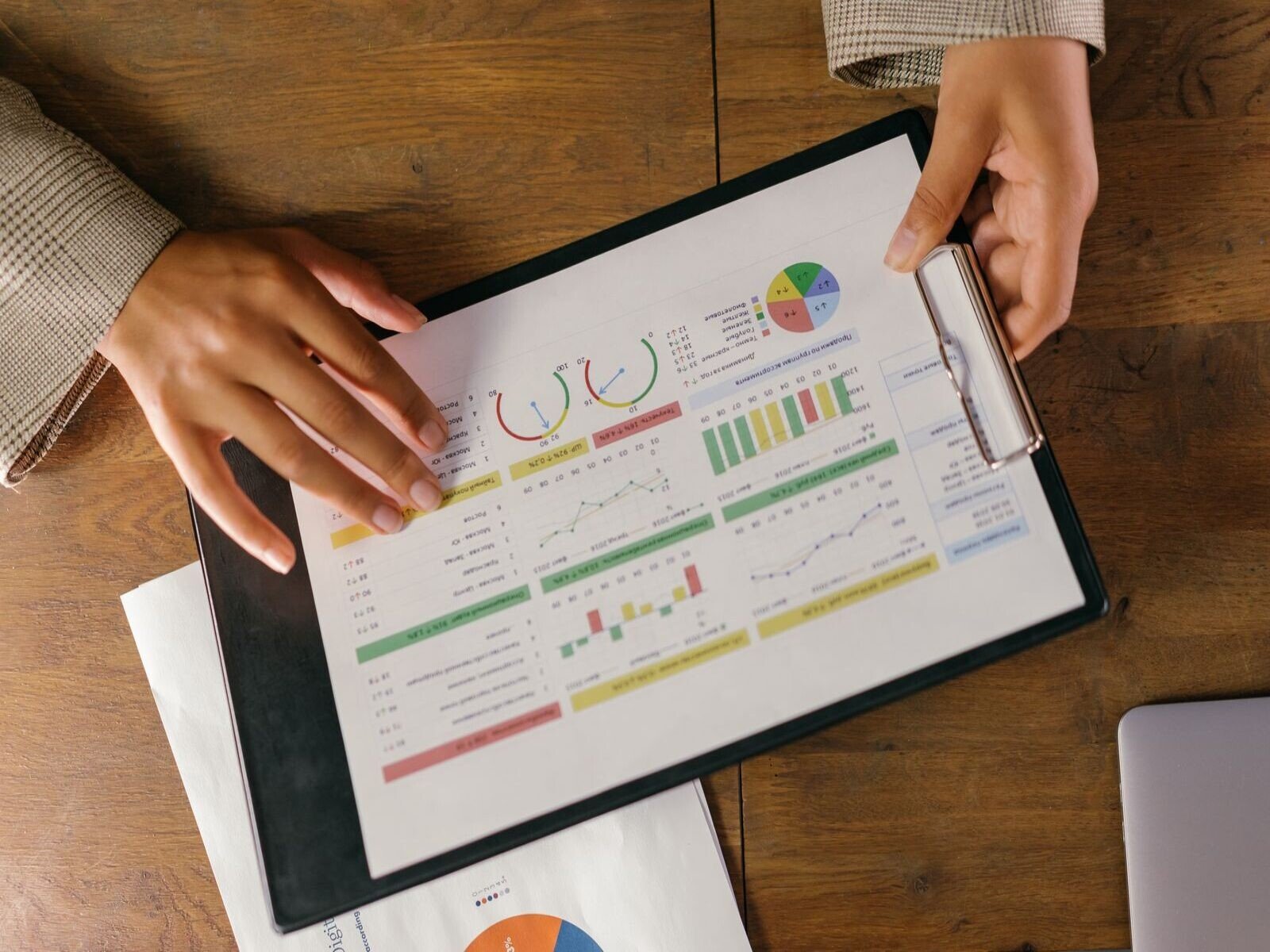 indicadores de gestión comercial, Top view of hands holding a financial report with colorful graphs and charts, ideal for business presentations.