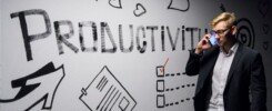 PNL y productividad, man holding smartphone looking at productivity wall decor