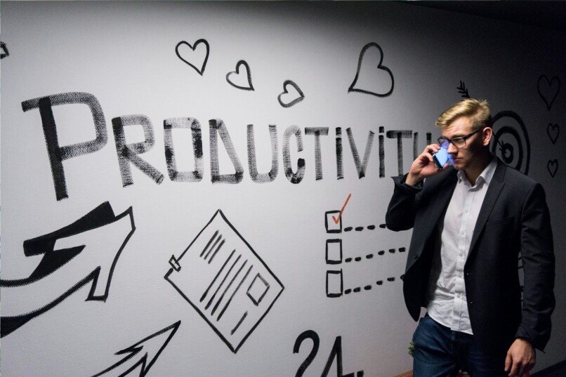 PNL y productividad, man holding smartphone looking at productivity wall decor