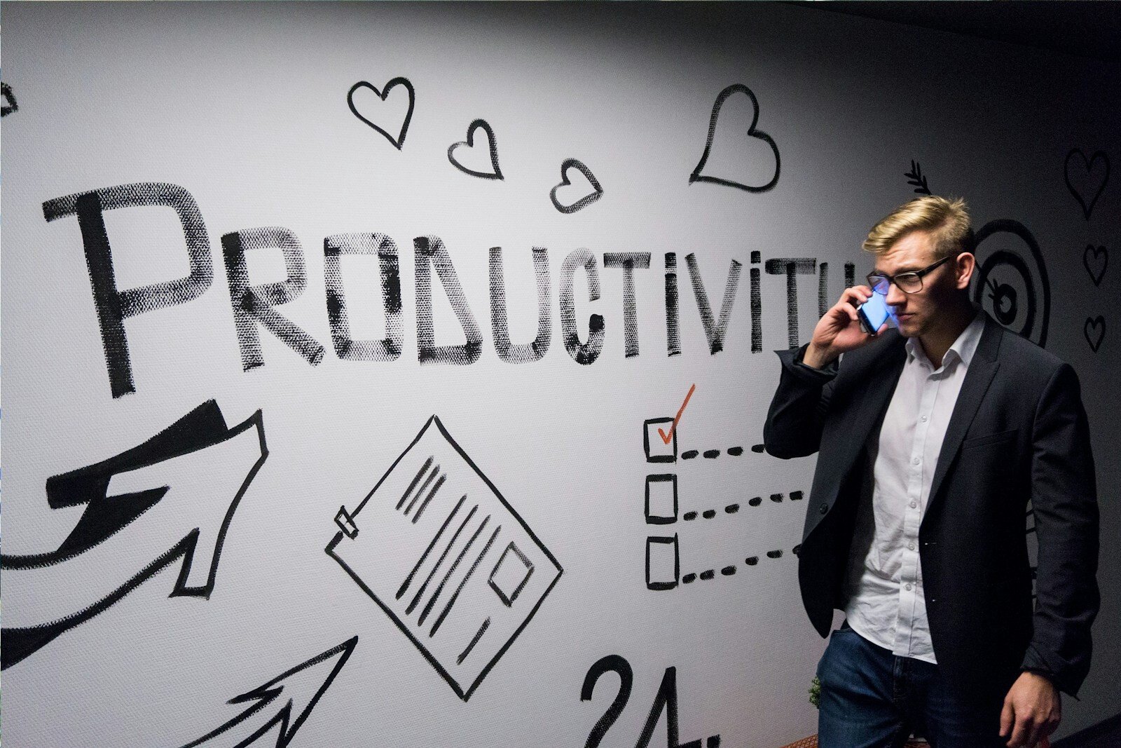 PNL y productividad, man holding smartphone looking at productivity wall decor