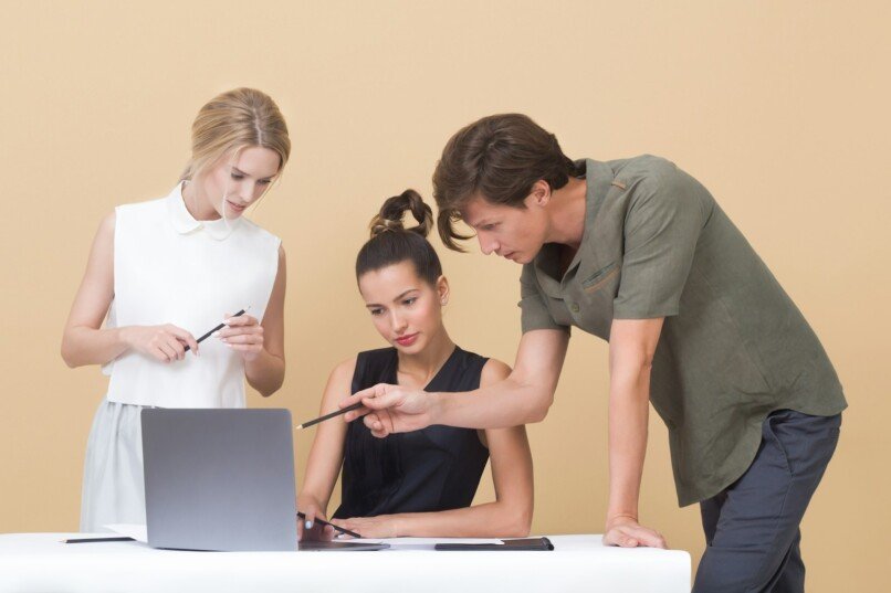 estrategia organizacional, man teaching woman while pointing on gray laptop
